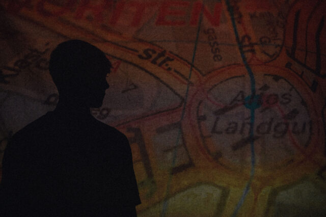 Schatten von Konstantin Aleksa vor einer Kartenprojektion des Alten Landguts