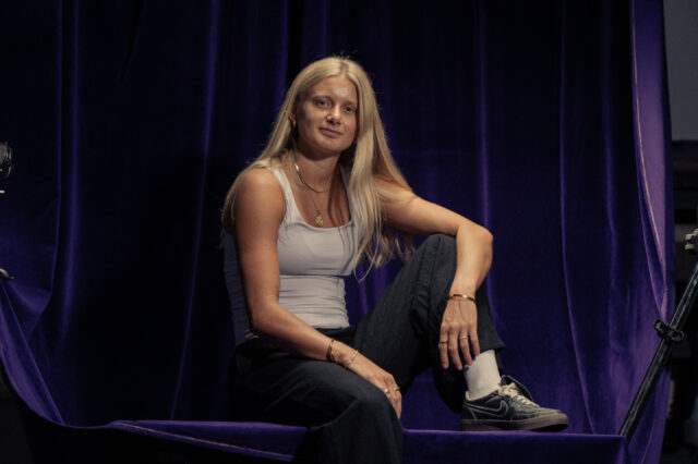 Sandra Jakobsen sitzt auf einem Tisch und blickt in die Kamera