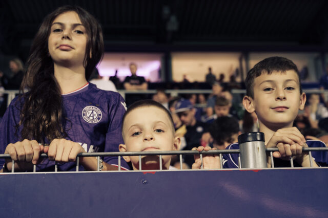 Fans schauen über den Tribünen-Zaun