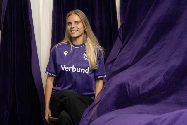 Louise Schöffel lacht umgeben von violetten Tüchern in die Kamera